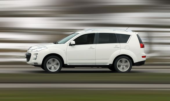 A panning shot of a speeding SUV