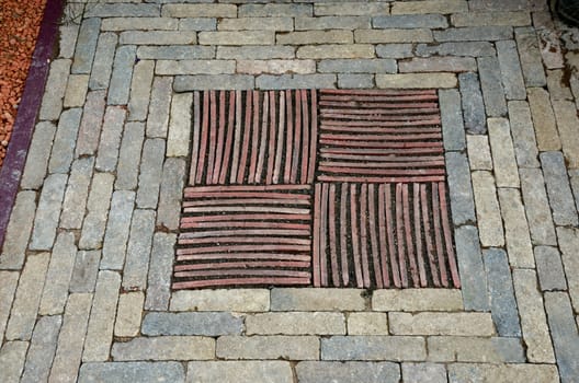 A close up view of decorative mosaic insert of stones bricks and tiles in a garden pathway