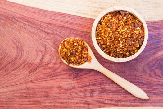 Spiced cayenne pepper in wooden bowl and spoon put on the table hardwood. Select Focus.