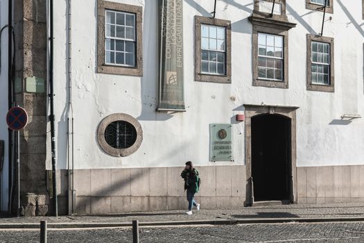 Porto, Portugal - November 30, 2018: Storefront and architectural detail of Lusofona de Porto University in the historic city center where people walk on a winter day