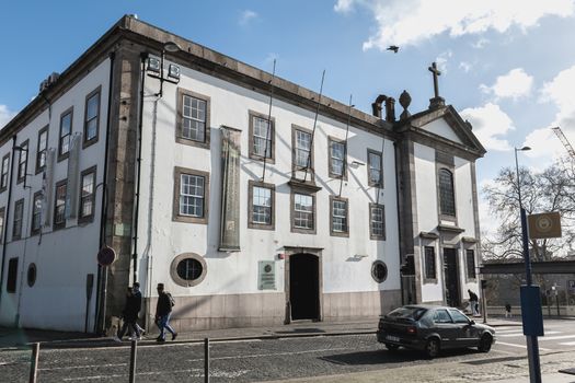 Porto, Portugal - November 30, 2018: Storefront and architectural detail of Lusofona de Porto University in the historic city center where people walk on a winter day