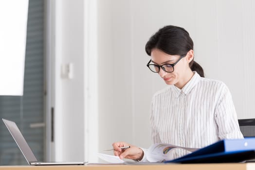 A businesswoman wearing glasses working with smiling and happiness at the office.