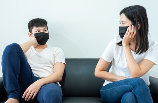 An Asian couple wearing a black mask and stays together with boring and social distancing.