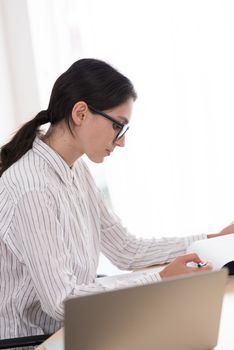 A businesswoman wearing glasses working with smiling and happiness at the office.