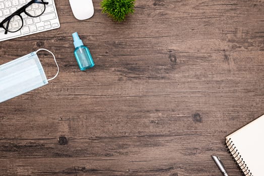 The equipment to protect COVID-19, blue mask and hand cleaner gel for preparing to work from home Isolated on wood desk.