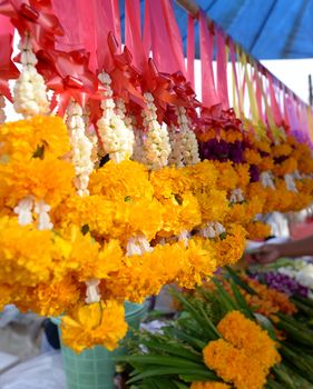 The garland is made of bright yellow flowers, Was hung for sale in the market, blurred background.
