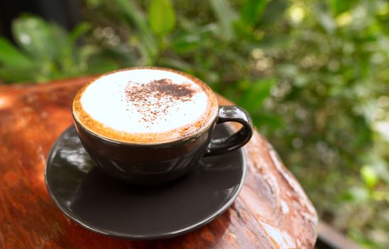 Hot mocha coffee or Cappuccino in the brown cup on the wooden table.