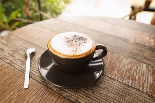 Hot mocha coffee or Cappuccino in the brown cup on the wooden table.