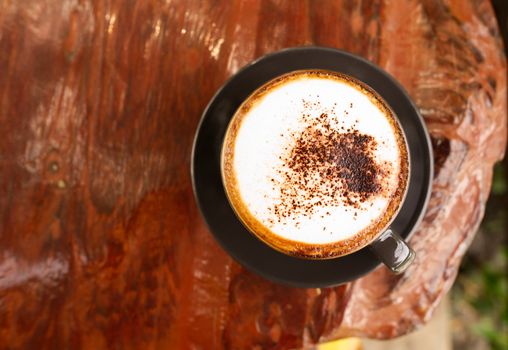 Hot mocha coffee or Cappuccino in the brown cup on the wooden table.