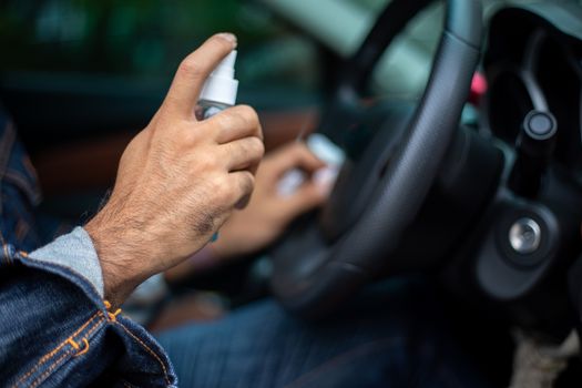 Asian man using spray alcohol to clean the car for coronavirus protection