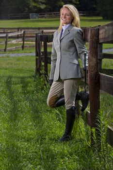 A blonde equestrian model poses outdoors before a horse show