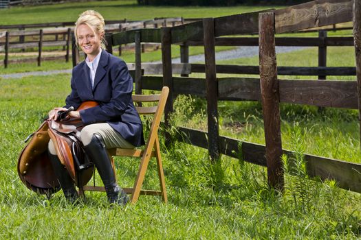 A blonde equestrian model poses outdoors before a horse show
