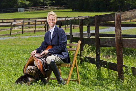 A blonde equestrian model poses outdoors before a horse show