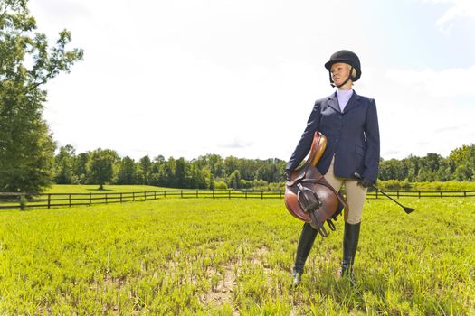 A blonde equestrian model poses outdoors before a horse show