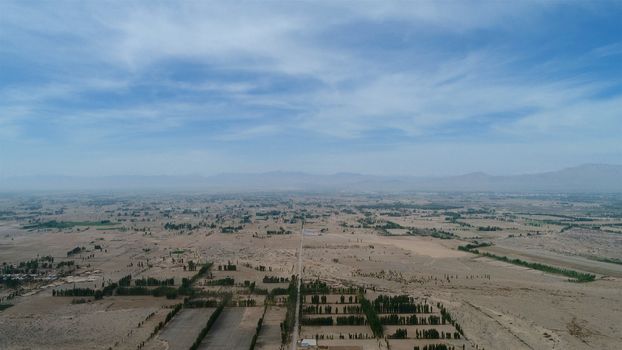 Aerial view of small poor village with school in the middle of dry farmland, Gansu, China