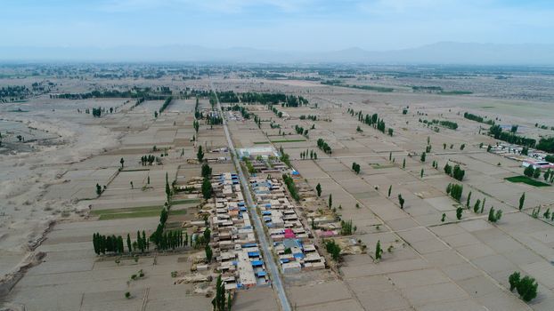 Aerial view of small poor village with school in the middle of dry farmland, Gansu, China