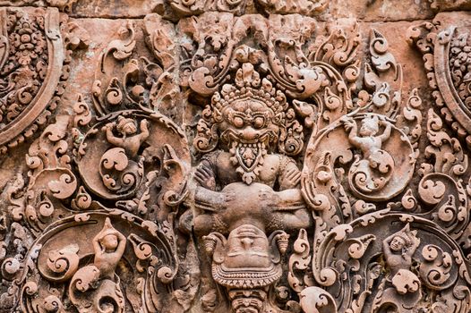 Ancient Khmer carving sandstone showing the Hindu god Vishnu in the guise of the lion man Narasimha clawing the demon Hiranyakashipu. Lintel at Banteay Srei temple, built 967 in Angkor, Cambodia.