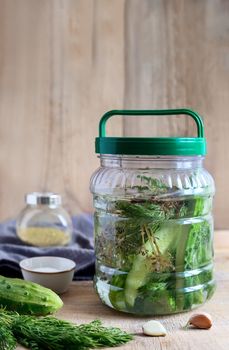 On the table in a glass jar lightly salted cucumbers in cucumber brine with spices: garlic, dill, black pepper.