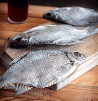 On a wooden table on a cutting Board dried fish, standing next to a glass of beer.