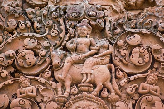 The Hindu god Shiva with his companion Parvati riding on the sacred bull Nandi. Ancient Khmer sandstone carving at the temple of Banteay Srei, part of the Angkor World Heritage Site.