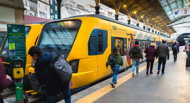 Porto, Portugal - November 30, 2018: Interior of Porto Sao Bento train station where people walk on the dock near the train stationary on a winter day