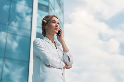 Businesswoman successful woman business person standing outdoor corporate building exterior cell phone Pensive elegance cute caucasian professional business woman middle age dreaming with mobile phone