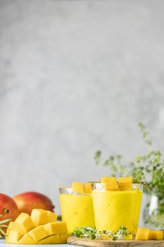 Yellow Indian mango yogurt drink Mango Lassi or smoothie with turmeric and saffron. Healthy probiotic Indian cold summer drink on blue background.