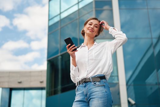 Businesswoman successful woman business person standing outdoor corporate building exterior cell phone Pensive elegance cute caucasian professional business woman middle age dreaming with mobile phone