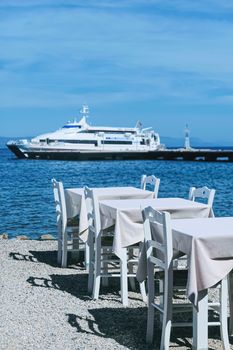 Empty restaurant by the Aegean sea and cruise boat, travel and nature, scene