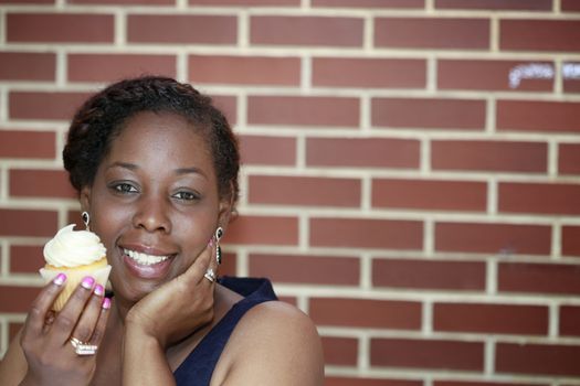 African American women holding cupcake on brick wall background