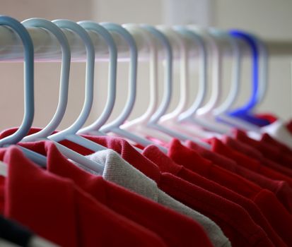 Red and one gray school uniform shirts on hangers.