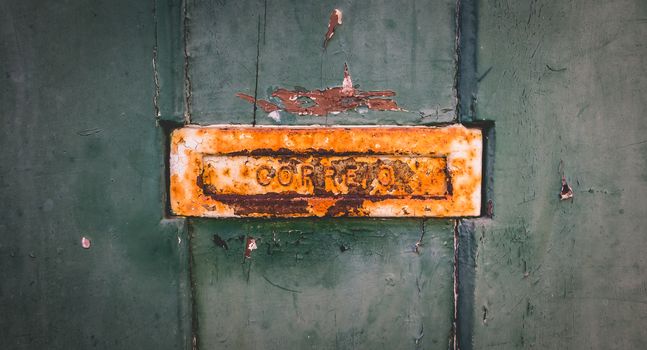 old rusty Portuguese mailbox on a worn wooden door where it is written in Portuguese: mail