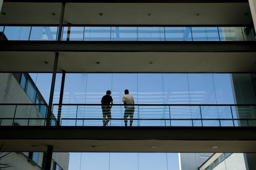 Silhouette view of two young men in a modern office building interior with panoramic windows.