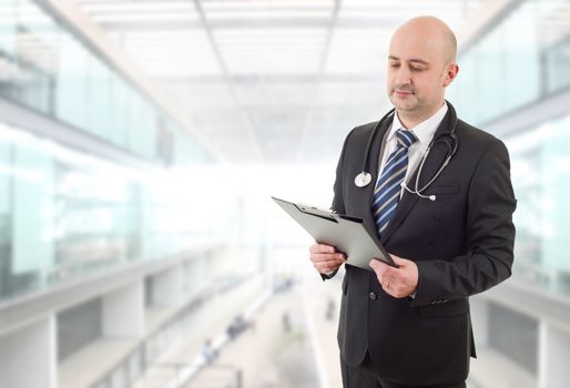 male doctor thinking with his notes, at the hospital