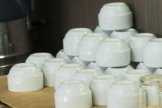 White cups for tea piled on table with plates for coffee-break