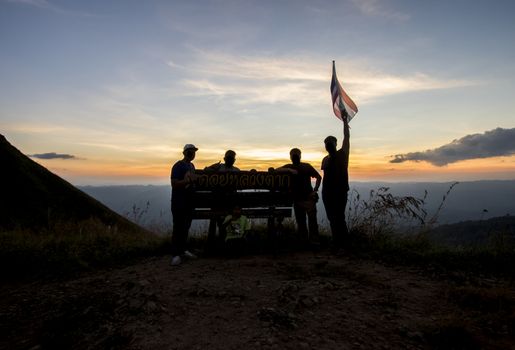 Silhouette of group of people at top of mountain at sunset