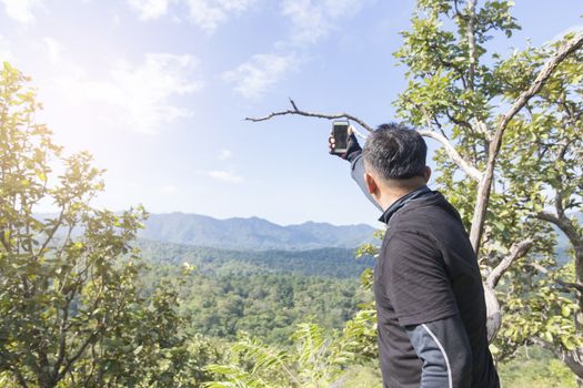 Asian man taking selfie on top of the mountain