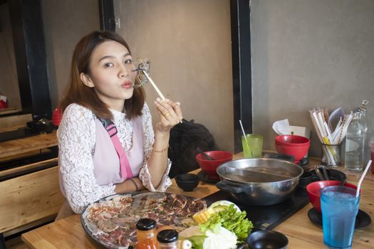 young asian woman enjoy eating Shabu-Shabu japanese hot pot