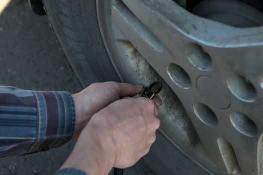 human hands insert the hose of the car pump to pump air into the wheel of the car