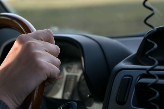 view of a people hand holding the wheel of a car, close-up