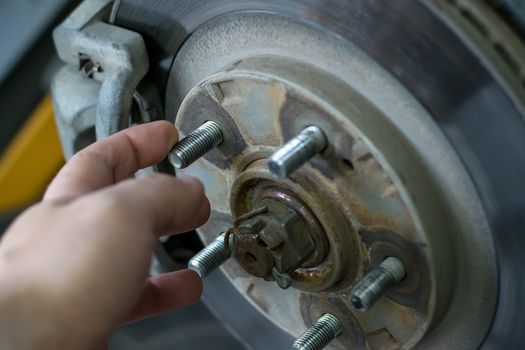 Brake discs wheels of the car with the caliper on the SRT. The human hand touches the bolt, close-up