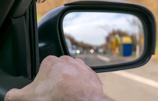 Hand man lying on the car door with a view from the window and with a view of the cars queue in the rear view mirror