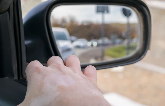 Hand man lying on the car door with a view from the window and with a view of the cars queue in the rear view mirror