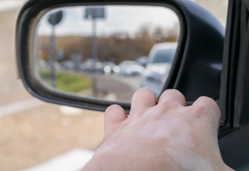 Hand man lying on the car door with a view from the window and with a view of the cars queue in the rear view mirror