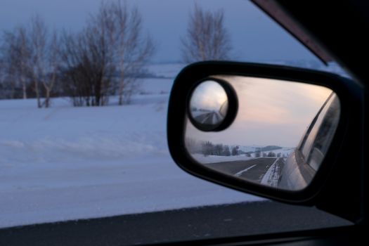 reflection in rear view mirror of night road, hills and sunset