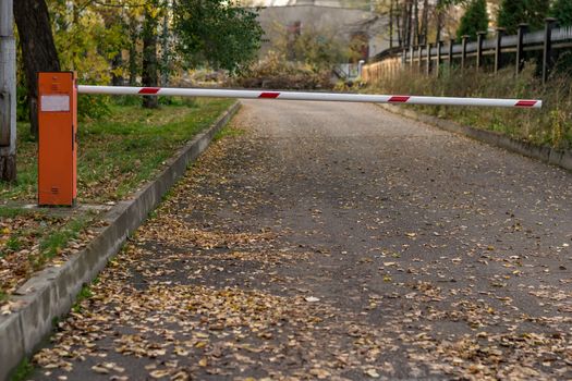 the barrier on the road leading to the building on the background of fallen autumn leaves