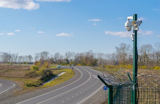 view camera fixing the movement of cars from speeding, which stands on a country road in the summer on the background of passing cars