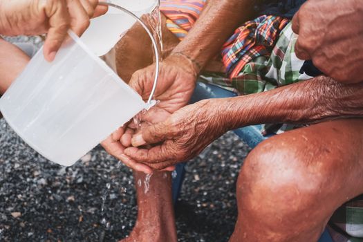 Person pour water on the hands of elders in family for doing respected and ask for blessing in Thai Songkran festival. 