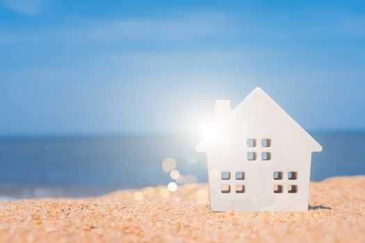 Model of a little house on sand with nature beach background. Dream life concept.