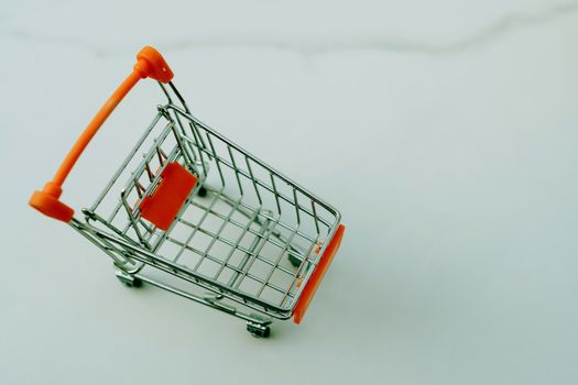 Shopping cart on marble white floor texture.
